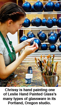 Chrissy is hand painting one of Leslie Hand Painted Glass's many types of glassware in its Portland, Oregon studio.