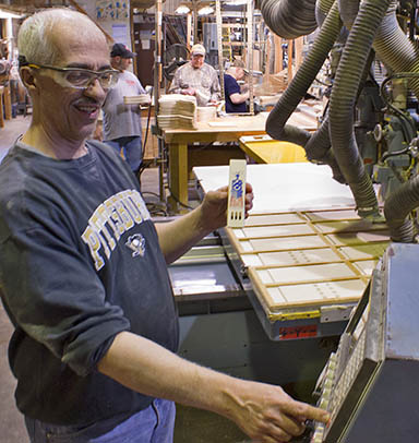 A worker runs a machine in the process of making Channel Craft's train whistle, while others work on the company's trademark boomerang.